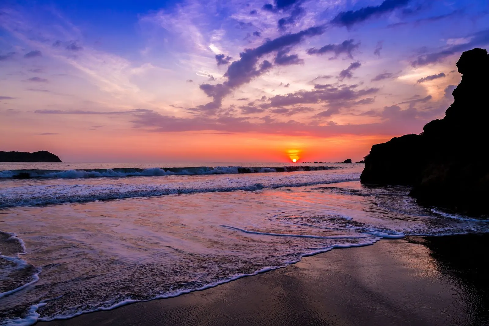 Atardecer sobre el Pacífico desde una playa de Manuel Antonio, con las olas sobre la arena