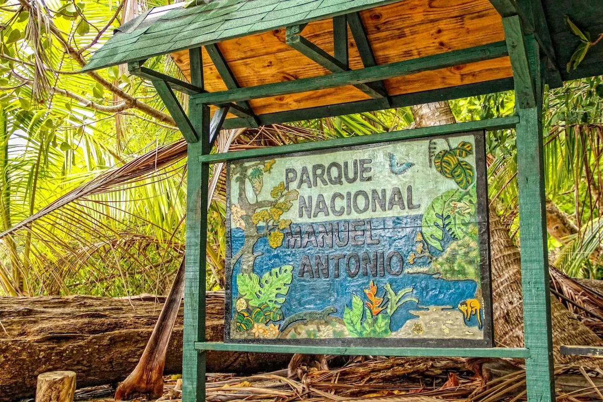 Painted Parque Nacional Manuel Antonio sign under a small wooden roof in the forest