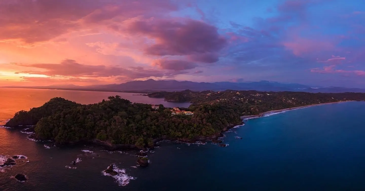 Vista aérea de Punta Quepos al atardecer, con el hotel entre el bosque sobre el Pacífico
