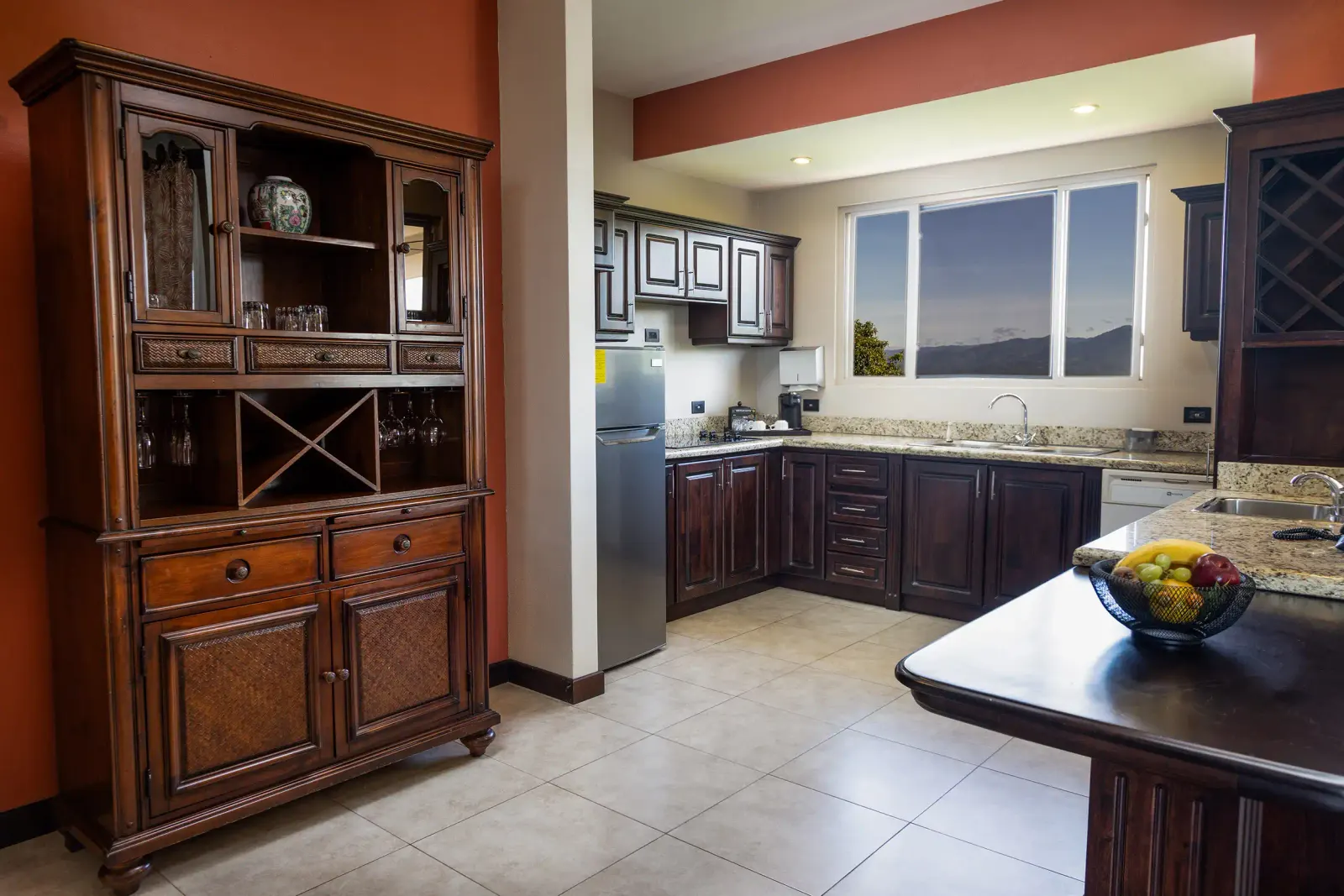 Penthouse kitchen with dark wood cabinets, a granite counter and a bowl of fruit