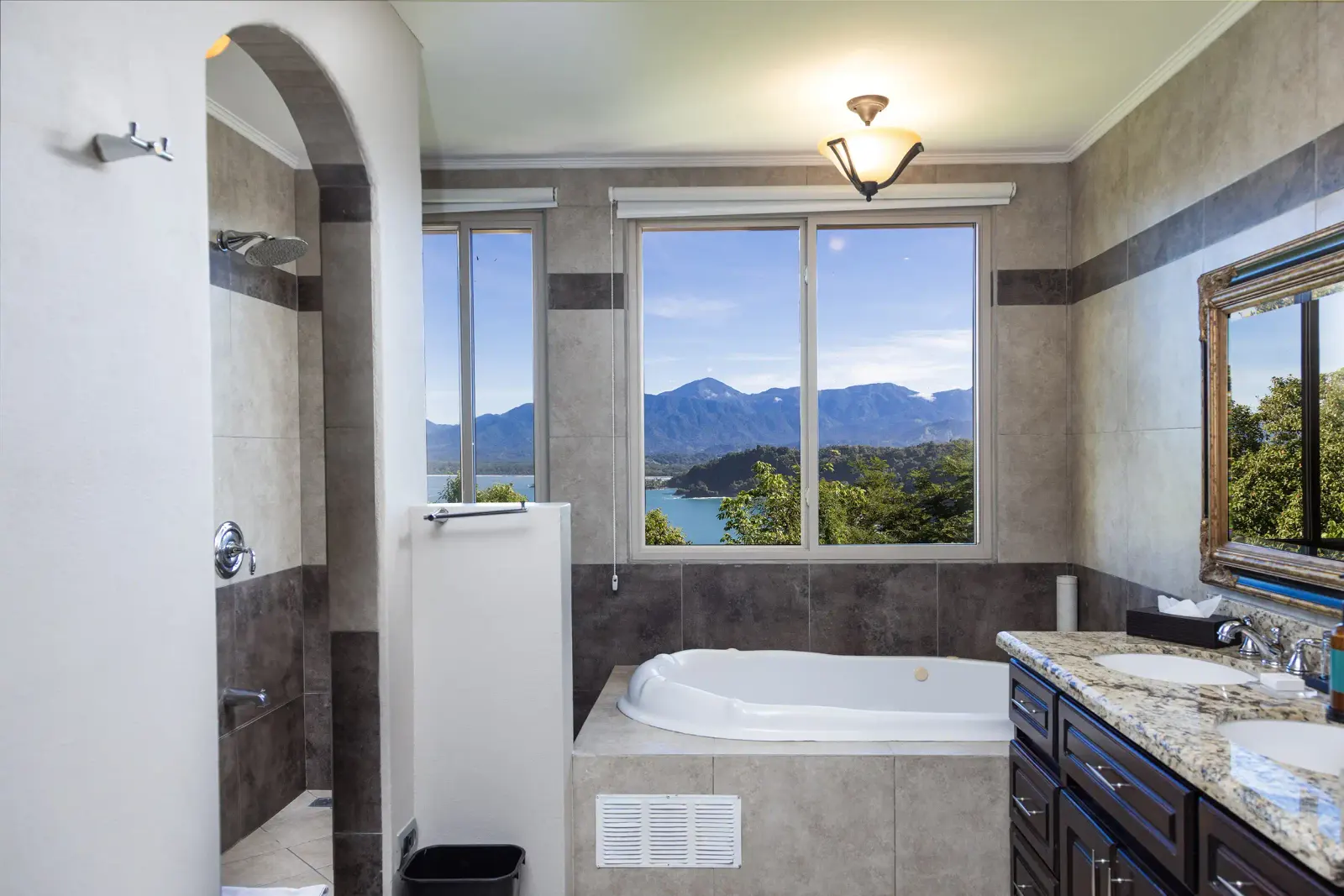 Penthouse bathroom with a jacuzzi tub under a window looking out to the mountains and the coast