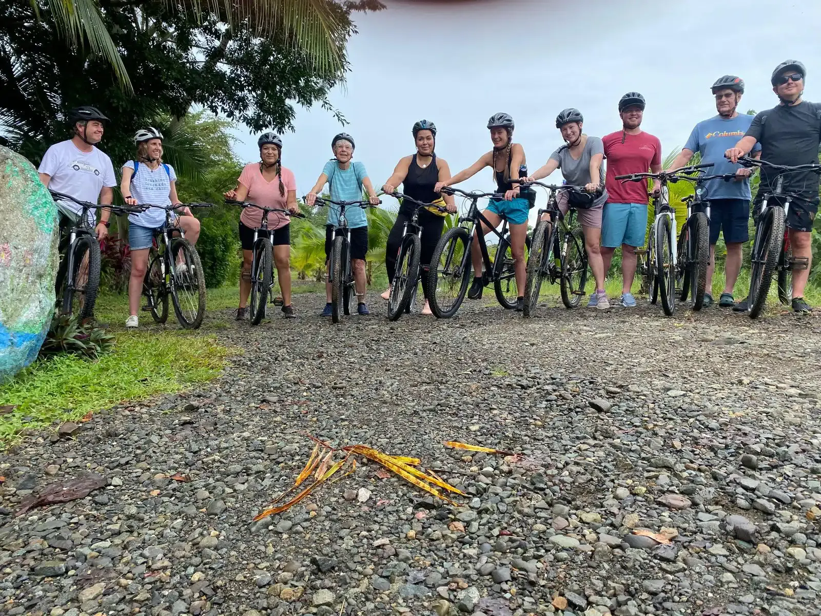 Grupo de ciclistas con casco de pie junto a sus bicicletas de montaña en un camino de lastre