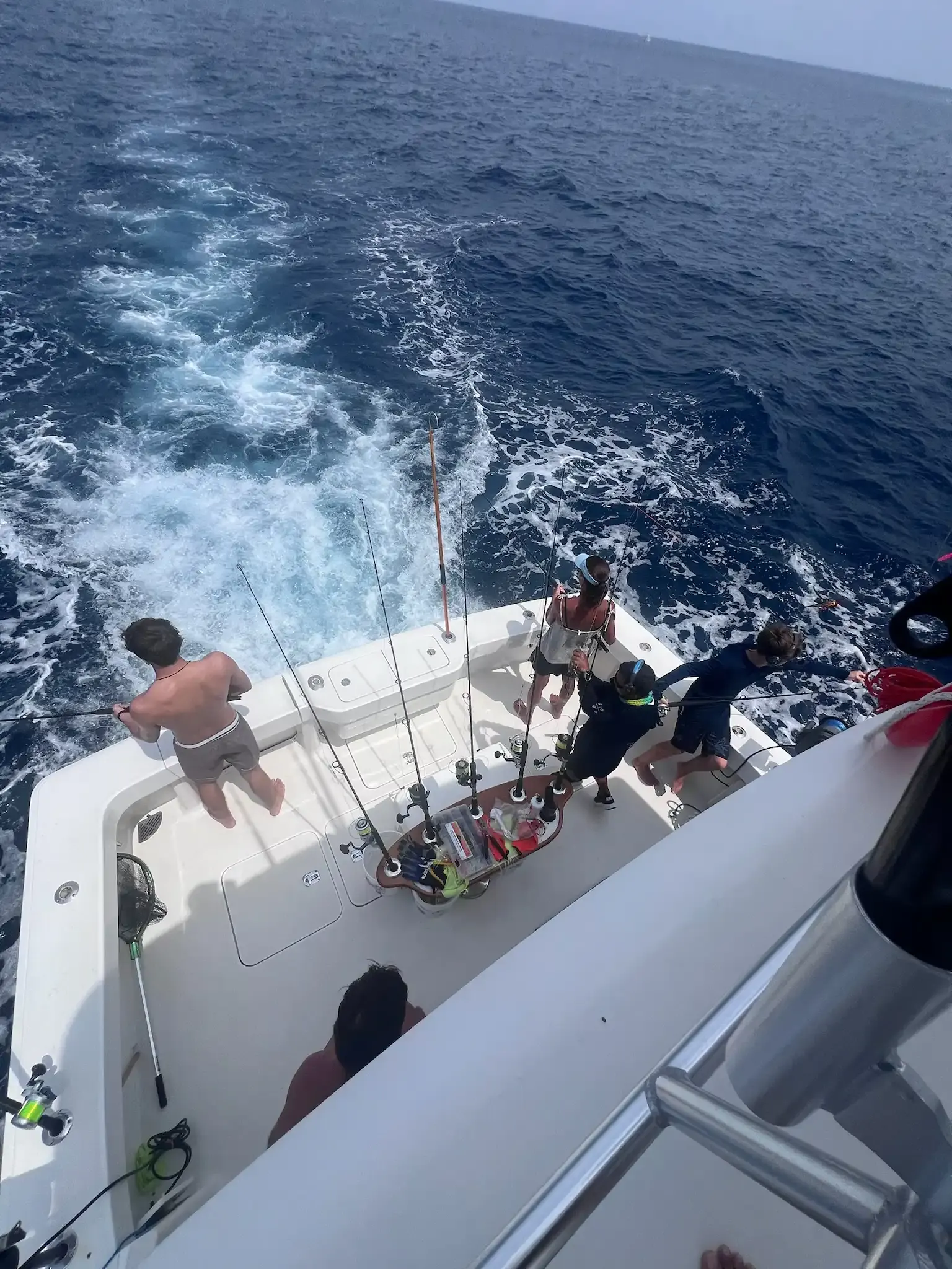 Anglers and crew at the stern of Vuelto Loco with rods out over a white wake