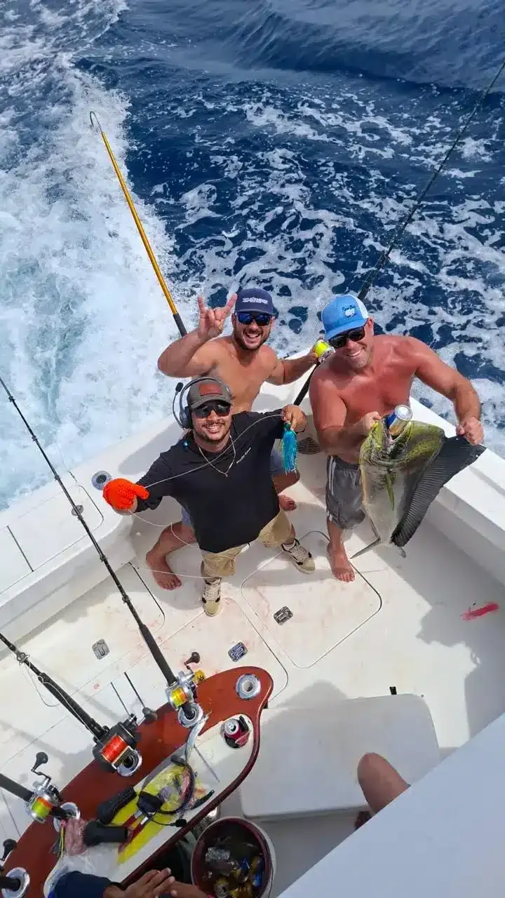 Three smiling anglers on the Vuelto Loco deck holding up a freshly caught dorado