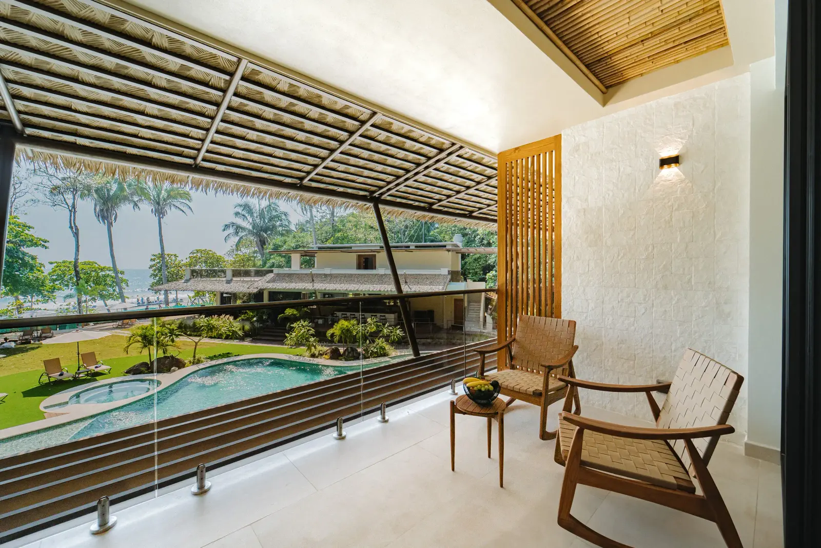 Terraza de una Balcony Suite en el segundo piso con sillas de madera, con vista sobre la piscina hacia el océano