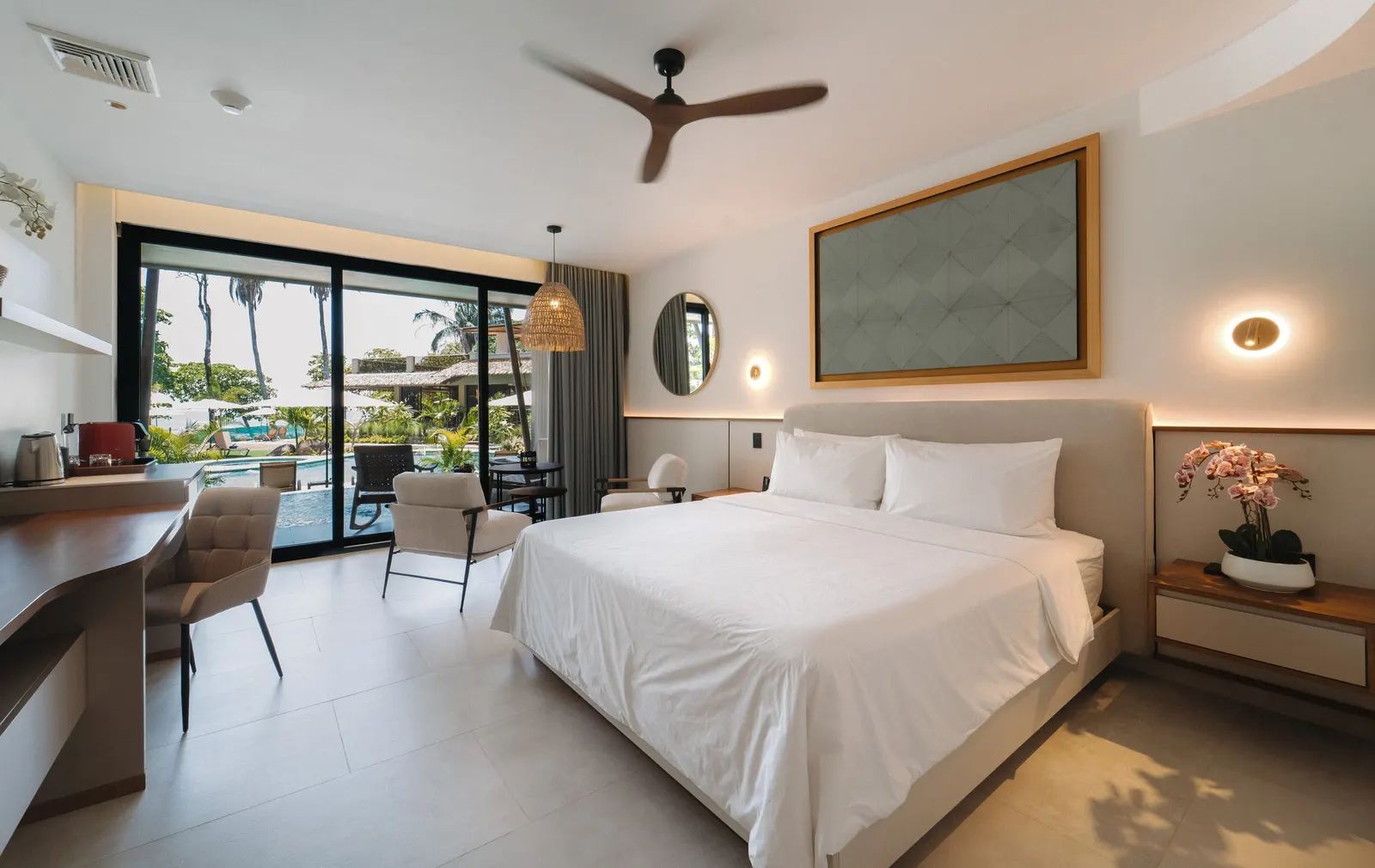 The bedroom of a Miamar water channel suite, glass doors open to the terrace and the pool