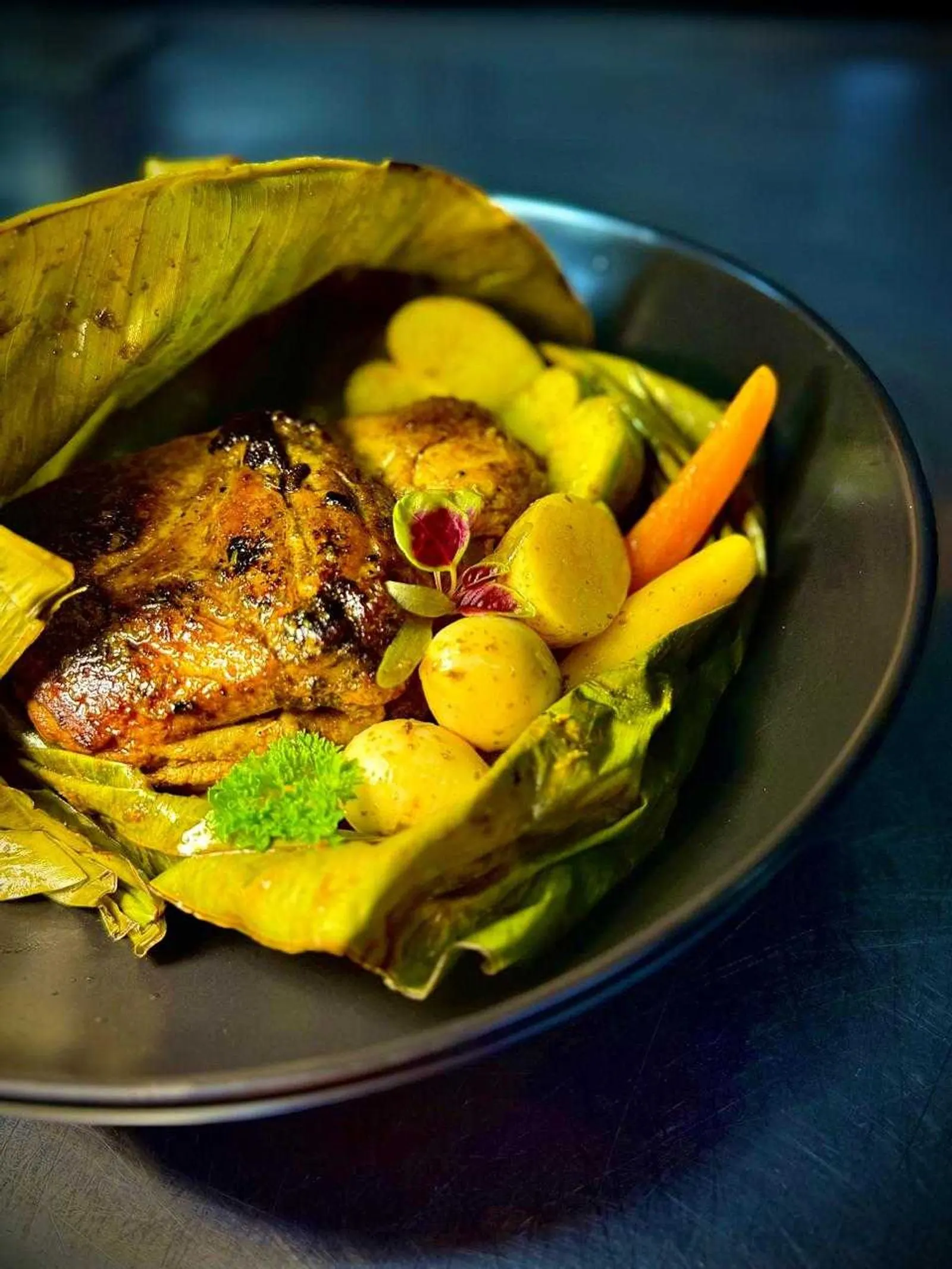 A dish served in a banana leaf with roasted potatoes and carrots