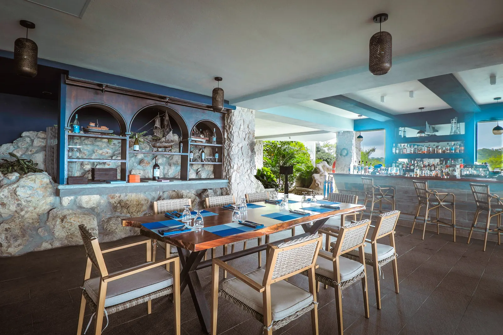 The bar at La Fragata, ship models in arched shelves beside a stone wall, a long table set in front
