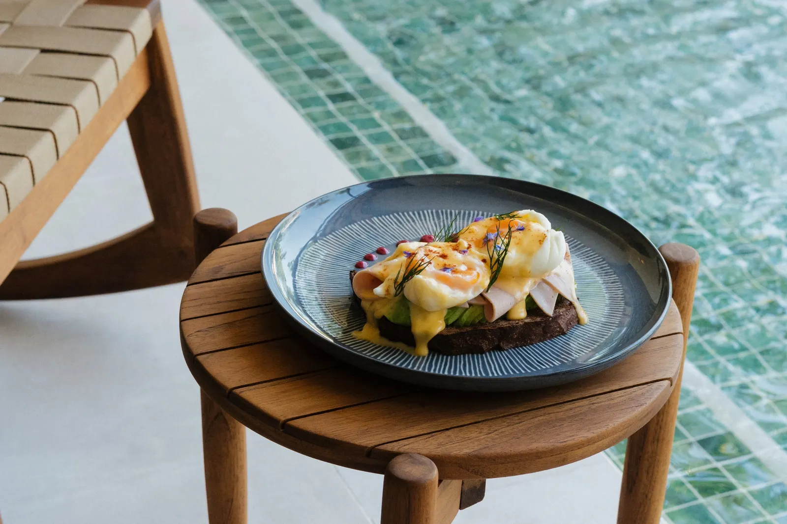 Huevos pochados sobre pan tostado con salsa holandesa, un desayuno servido junto a la piscina en Miamar