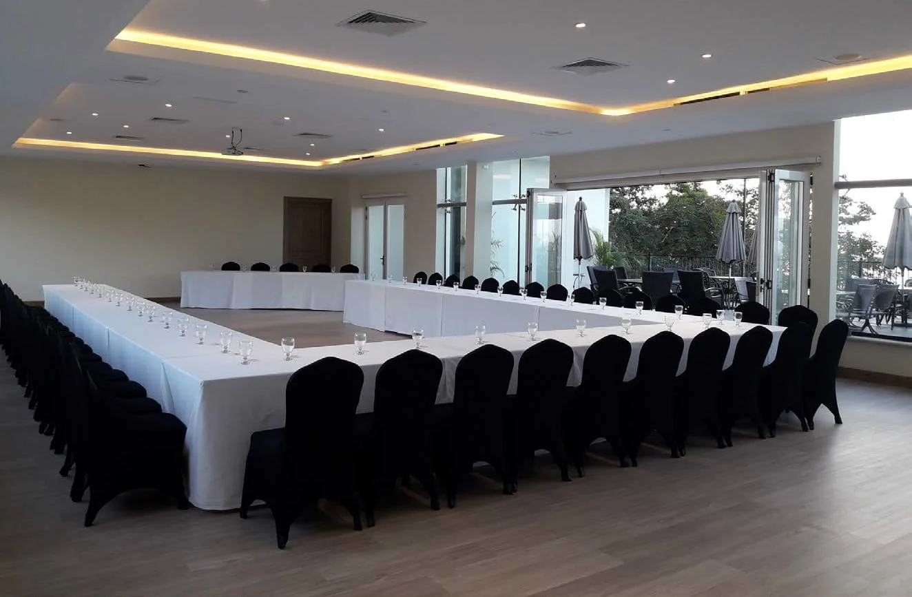 L'Orange Room set U-shape with black chair covers and full glassware, folding glass doors open to the terrace and rainforest canopy.