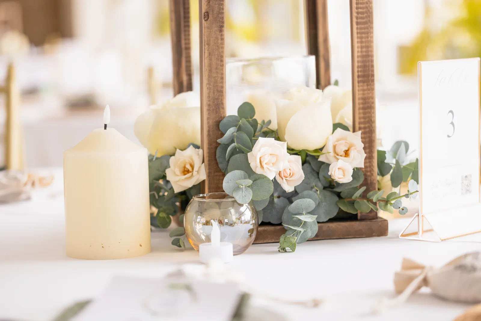 Centro de mesa de rosas blancas y rosa pálido con una vela encendida.