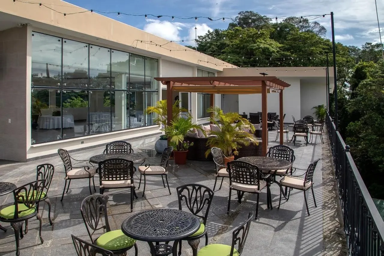 Rooftop lounge terrace at L'Orange with wicker seating under a wood pergola and café string lights, a spot for a retreat's evening downtime.