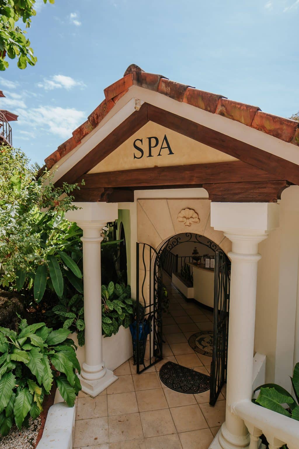 Entrance to the spa under a tiled roof, framed by plants