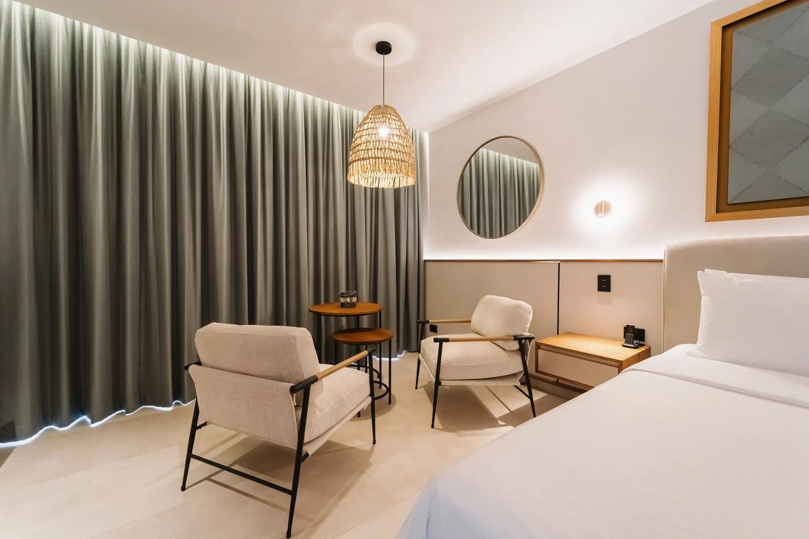 Sitting area in a Miamar suite with two armchairs, nesting side tables, and a woven pendant light.