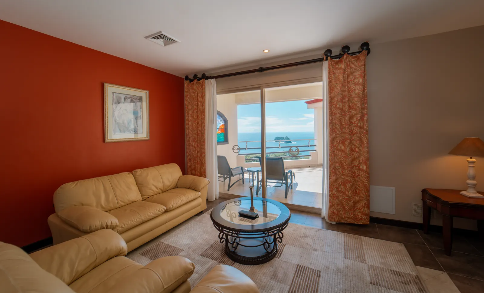 Penthouse living room at Parador with cream leather sofas and open sliding doors leading to a balcony overlooking the Pacific Ocean and rock islands